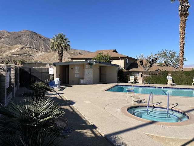 view of swimming pool with a patio area, a mountain view, and a hot tub