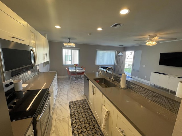 kitchen featuring appliances with stainless steel finishes, a healthy amount of sunlight, white cabinets, and sink