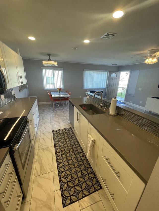 kitchen featuring ceiling fan, stainless steel appliances, a kitchen island with sink, white cabinets, and sink