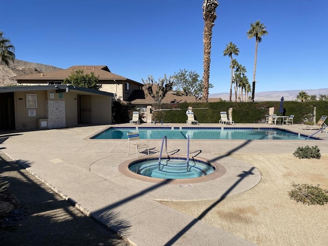 view of pool with a patio area, a mountain view, and a community hot tub