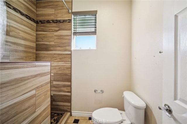 bathroom featuring toilet and a tile shower