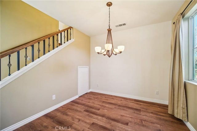 unfurnished dining area featuring hardwood / wood-style flooring and a notable chandelier