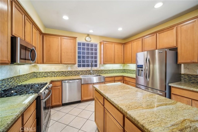 kitchen featuring stainless steel appliances, light stone counters, tasteful backsplash, and sink