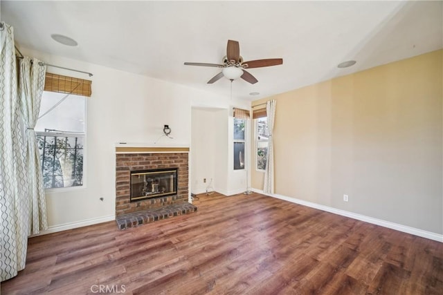 unfurnished living room with hardwood / wood-style flooring, a brick fireplace, and ceiling fan