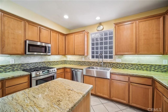 kitchen featuring sink, light stone countertops, appliances with stainless steel finishes, tasteful backsplash, and light tile patterned flooring