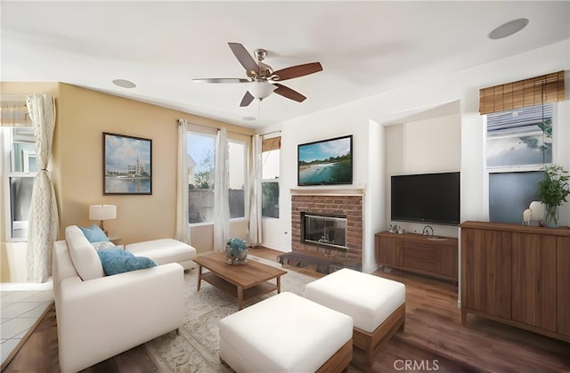 living room with a brick fireplace, ceiling fan, and hardwood / wood-style flooring