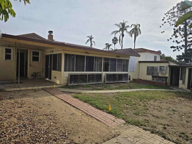 rear view of house with a patio area, a yard, and a sunroom