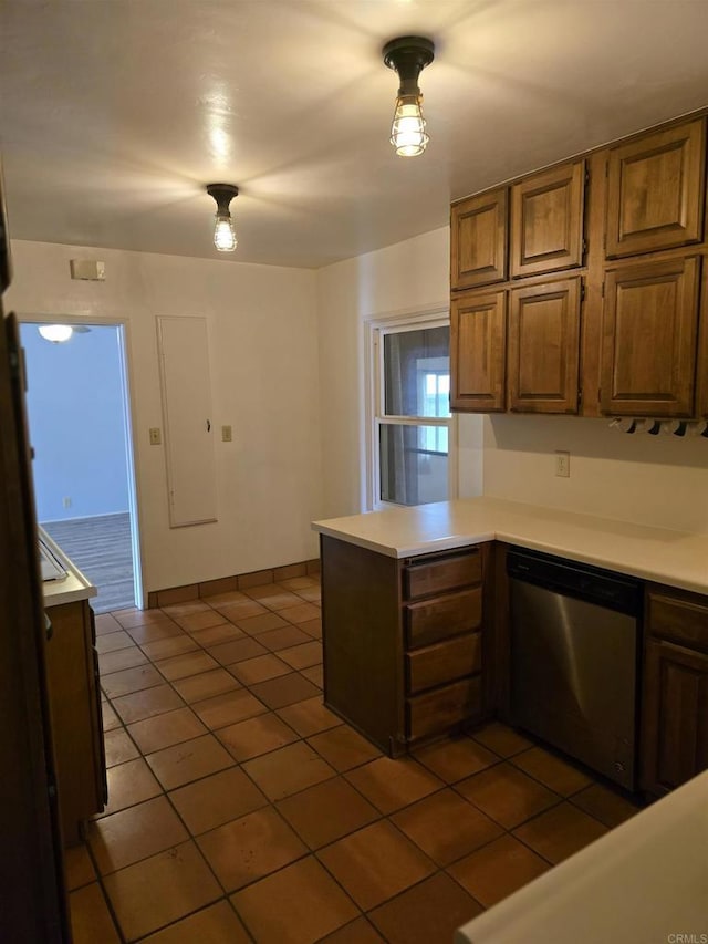 kitchen featuring dark tile patterned floors, dishwasher, and kitchen peninsula