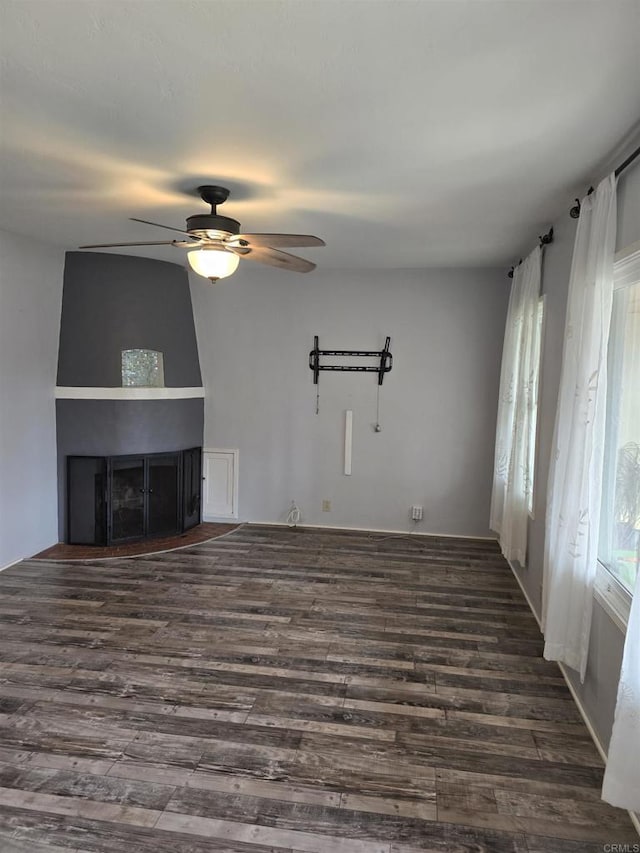 unfurnished living room with ceiling fan, dark wood-type flooring, and a fireplace