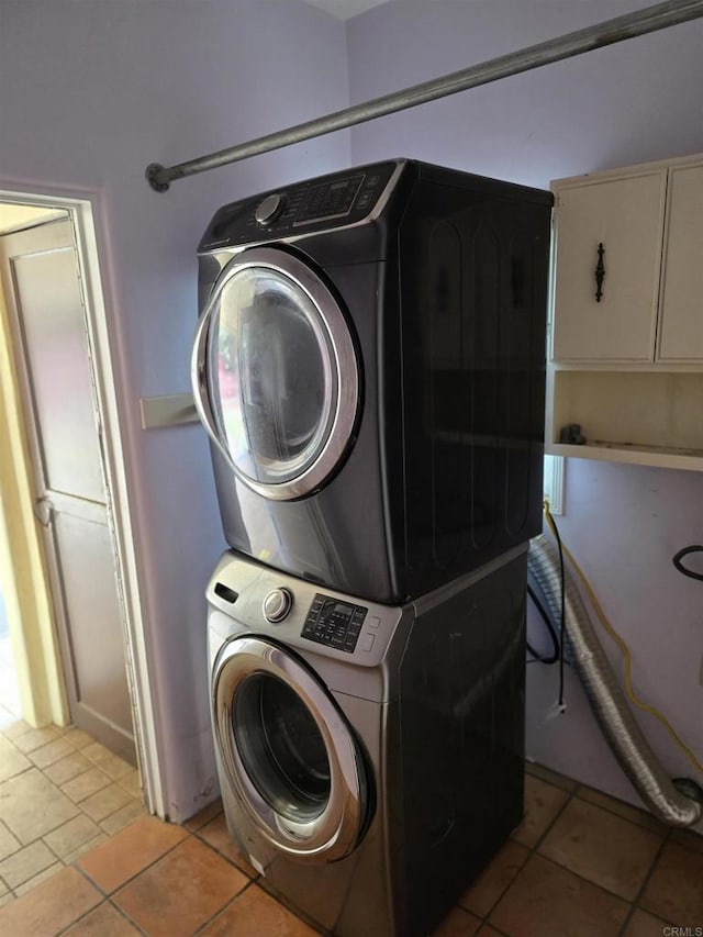 laundry area with stacked washing maching and dryer and light tile patterned floors