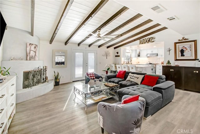 living room featuring ceiling fan, light hardwood / wood-style flooring, french doors, and vaulted ceiling with beams