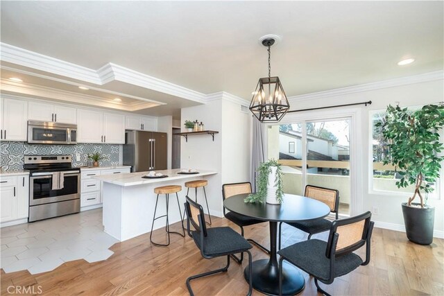 dining area featuring ornamental molding, light hardwood / wood-style floors, and a notable chandelier