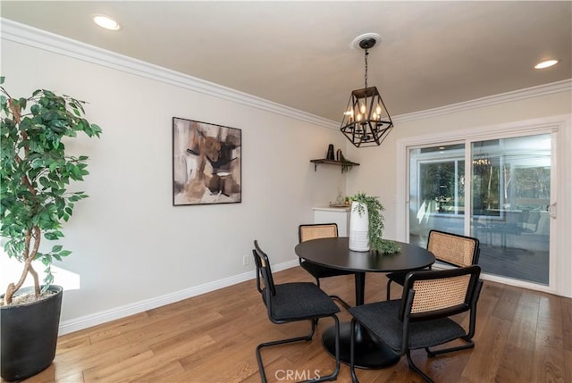 dining area with wood-type flooring, an inviting chandelier, and ornamental molding