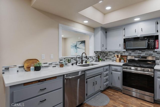 kitchen with tasteful backsplash, stainless steel appliances, sink, and gray cabinetry