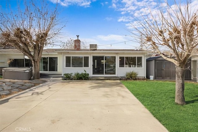 exterior space featuring a shed, a hot tub, a patio area, and a yard