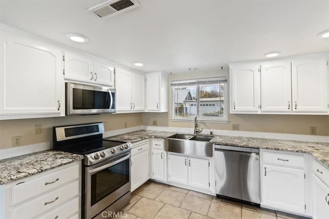 kitchen featuring light stone counters, sink, white cabinetry, and appliances with stainless steel finishes