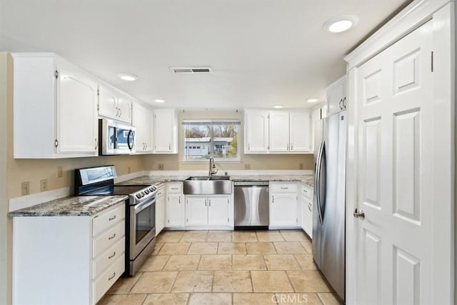 kitchen featuring light stone countertops, stainless steel appliances, white cabinets, and sink