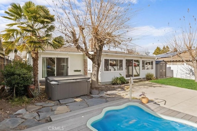 back of house with a hot tub, a storage shed, and a patio