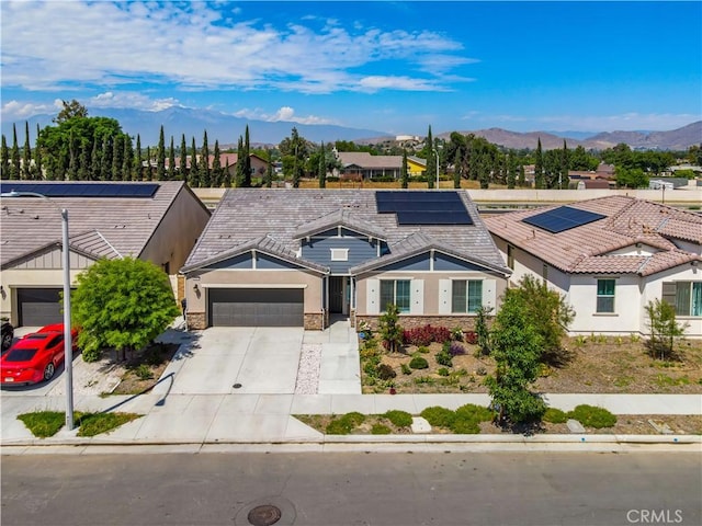 view of front of home with a mountain view, a garage, and solar panels