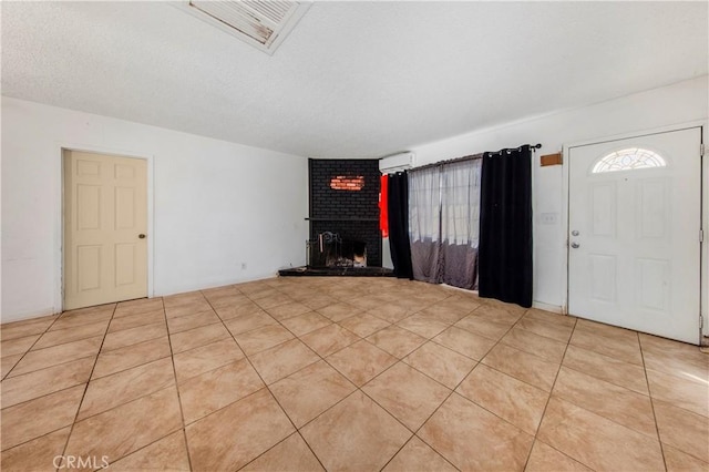 entrance foyer with a brick fireplace, a textured ceiling, light tile patterned floors, and a wall mounted AC