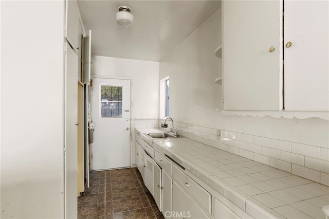 kitchen with white cabinetry, tile countertops, decorative backsplash, and sink