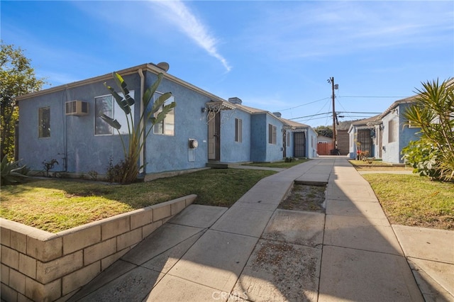 view of property exterior featuring a wall mounted AC and a yard