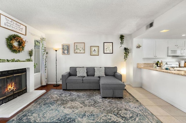 tiled living room featuring a textured ceiling and a fireplace