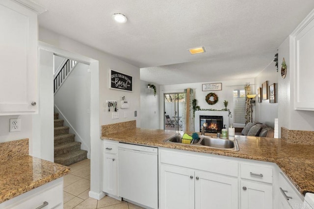 kitchen featuring light tile patterned floors, kitchen peninsula, white dishwasher, white cabinets, and sink