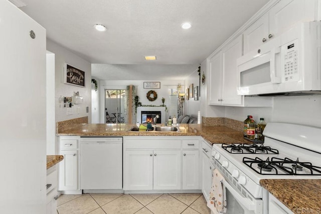 kitchen featuring stone counters, sink, white appliances, white cabinetry, and light tile patterned floors