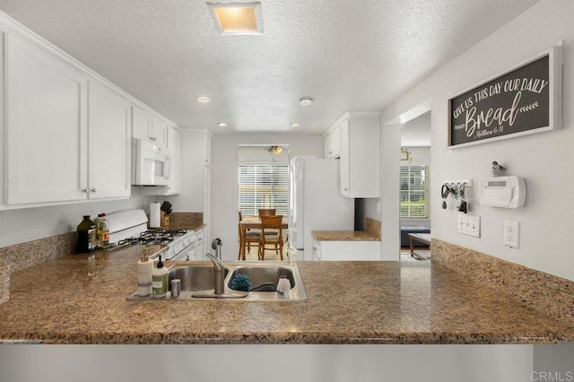 kitchen featuring dark stone countertops, sink, white appliances, and white cabinetry