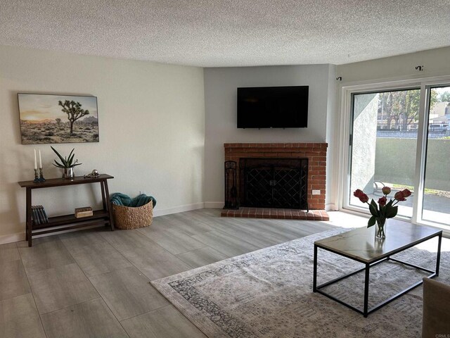 living room with a textured ceiling, hardwood / wood-style flooring, and a brick fireplace