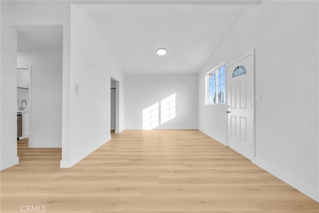 corridor with lofted ceiling, sink, and light hardwood / wood-style floors