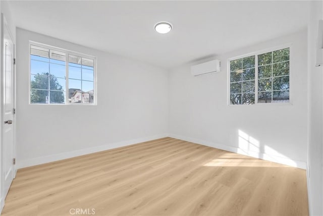 unfurnished room with a wall mounted air conditioner and light hardwood / wood-style flooring