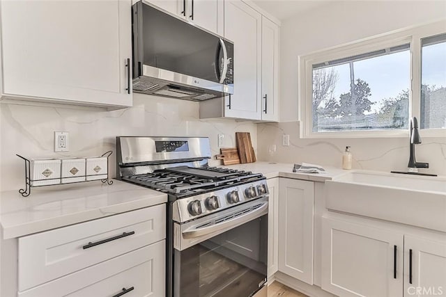 kitchen with white cabinetry, sink, light stone countertops, and appliances with stainless steel finishes