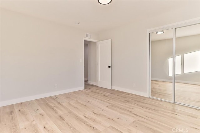 unfurnished bedroom with light hardwood / wood-style flooring and a closet