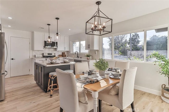 dining room with light wood-type flooring, sink, and a chandelier