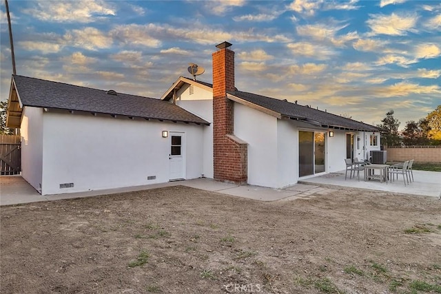 back house at dusk with central air condition unit and a patio