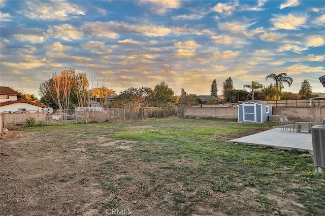 yard at dusk featuring a patio and a storage shed