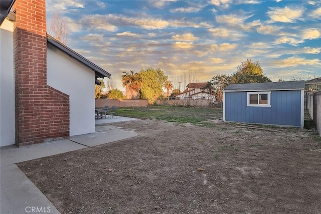 yard at dusk with a storage shed and a patio area