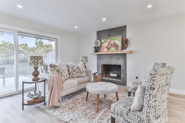 living room featuring a tile fireplace and light hardwood / wood-style floors