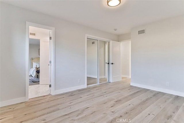 unfurnished bedroom featuring light wood-type flooring and a closet