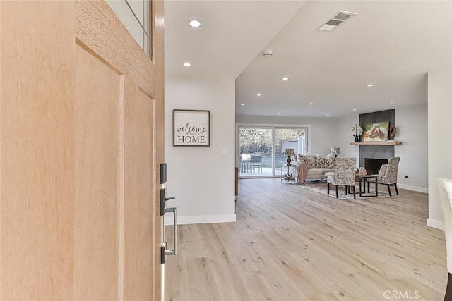 entrance foyer with a large fireplace and light hardwood / wood-style flooring