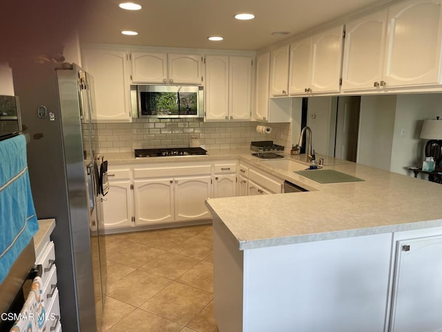 kitchen featuring white cabinetry, appliances with stainless steel finishes, kitchen peninsula, and sink