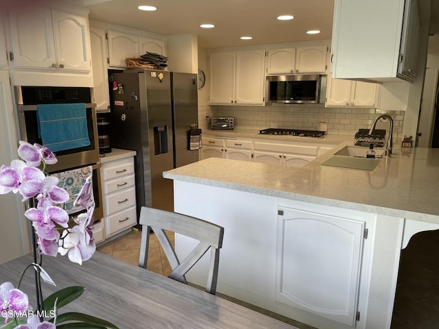 kitchen featuring white cabinets, appliances with stainless steel finishes, a kitchen breakfast bar, kitchen peninsula, and light tile patterned floors