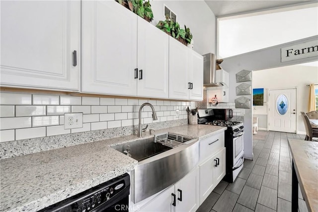 kitchen with light stone counters, white cabinets, gas range oven, and wall chimney exhaust hood