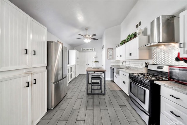 kitchen featuring a breakfast bar, white cabinetry, appliances with stainless steel finishes, and wall chimney exhaust hood