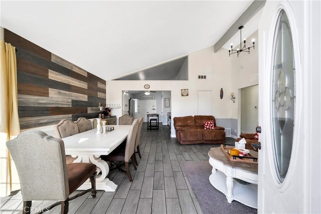 dining area featuring an inviting chandelier, wood walls, and vaulted ceiling with beams