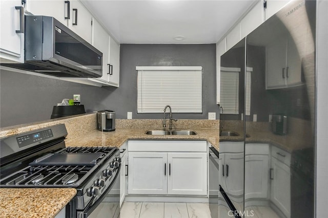 kitchen with light stone countertops, stainless steel appliances, white cabinetry, and sink