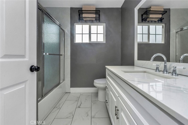 full bathroom with toilet, a healthy amount of sunlight, vanity, and bath / shower combo with glass door