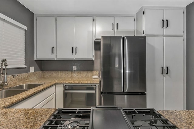 kitchen featuring sink, white cabinetry, and stainless steel refrigerator